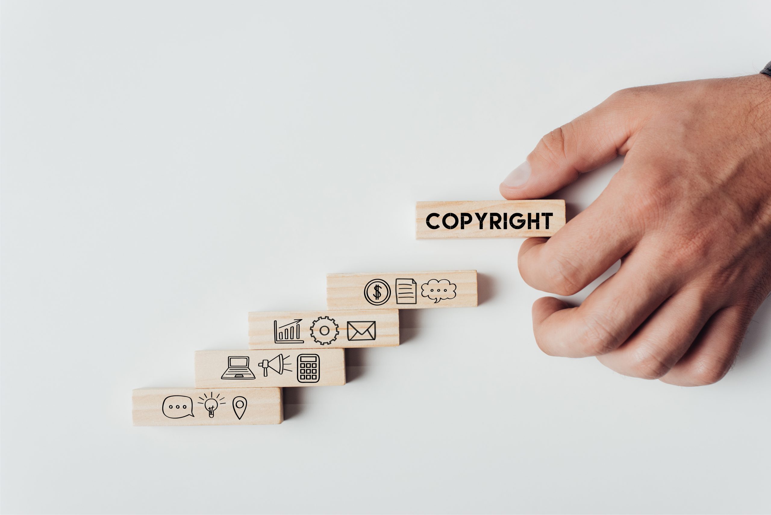 cropped view of man holding wooden block with word 'copyright' on top of wooden bricks with icons